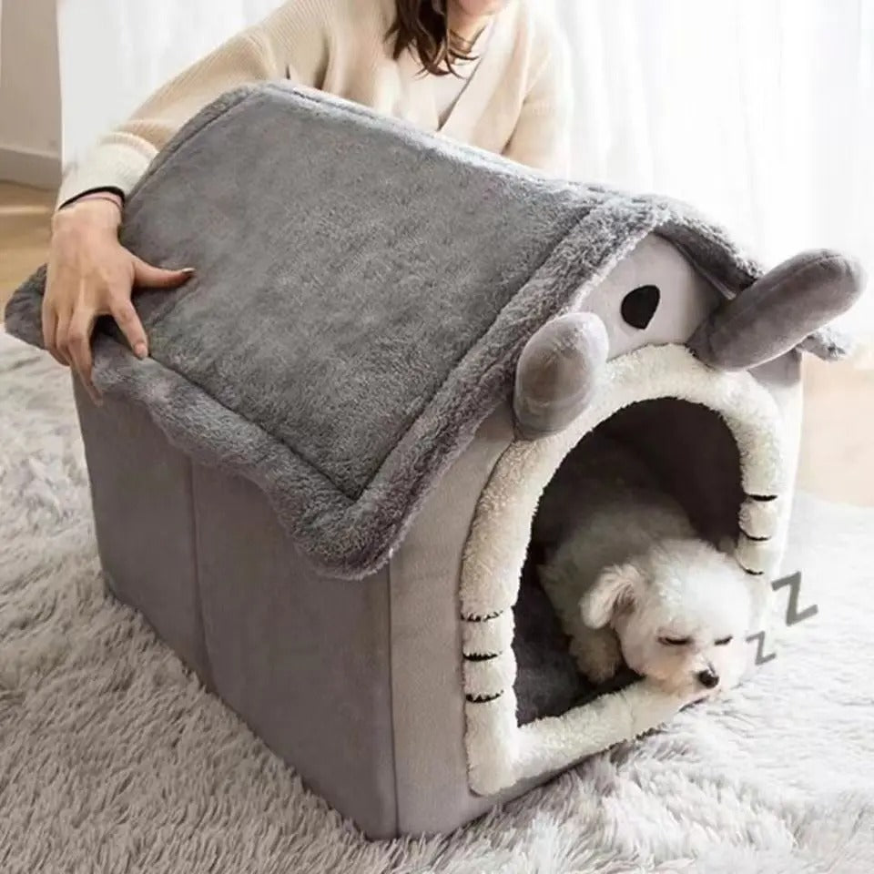 Person holding a gray pet house with a small white dog inside on a fluffy rug.